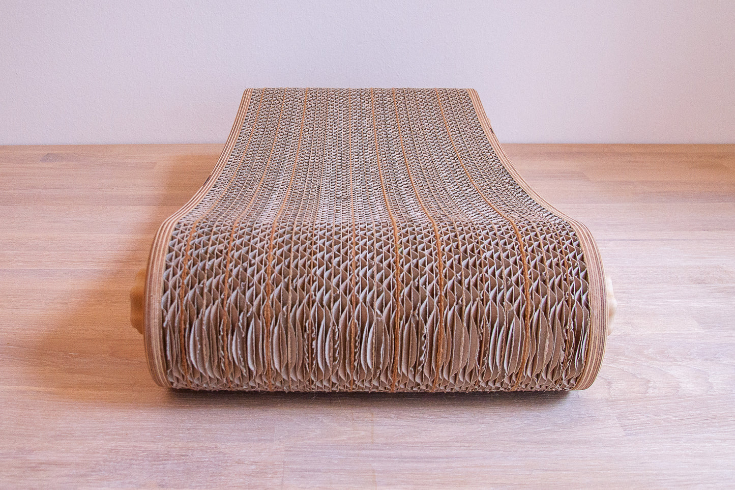 Kratzmöbel für Katzen in Form einer Liege bestehend aus zwei hellen Holzelementen mit Wellpappebögen dazwischen. Die Verschraubung erfolgt mit Muttern aus Holzfilament in Form von abgerundeten Sternen.